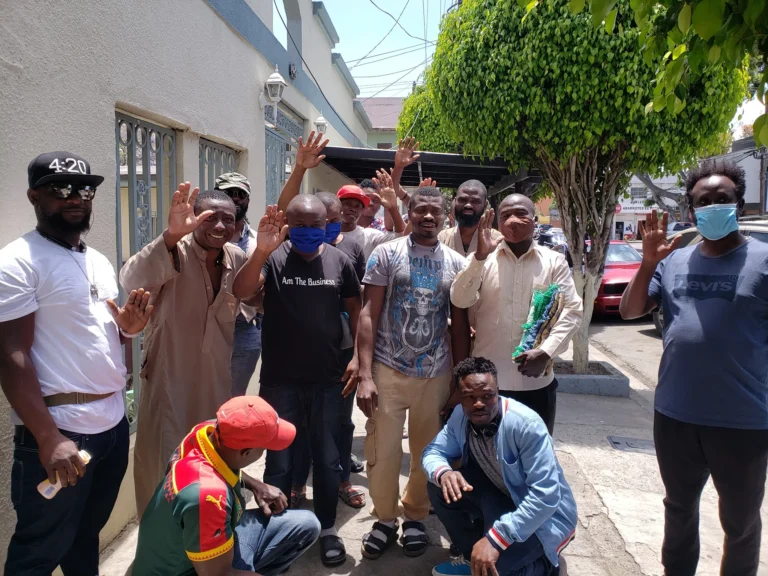 A group of men smiling and waving together outdoors