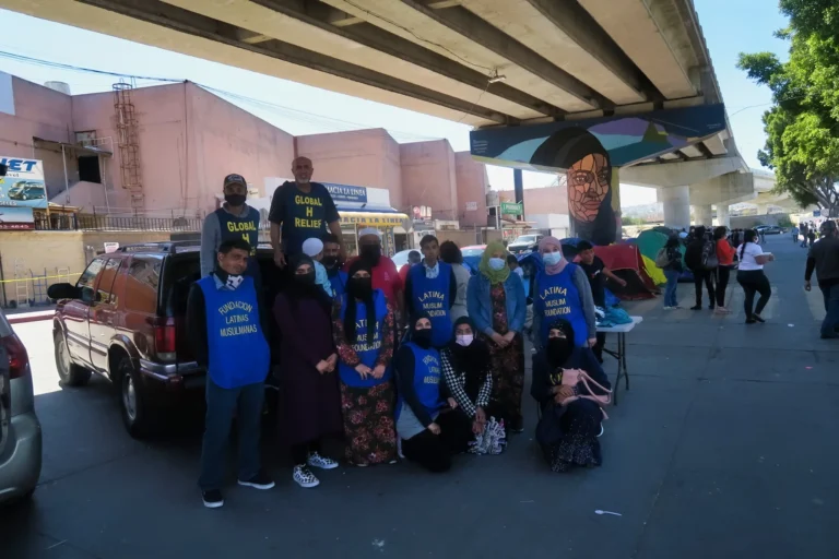 Volunteers in blue vests with families at a street outreach