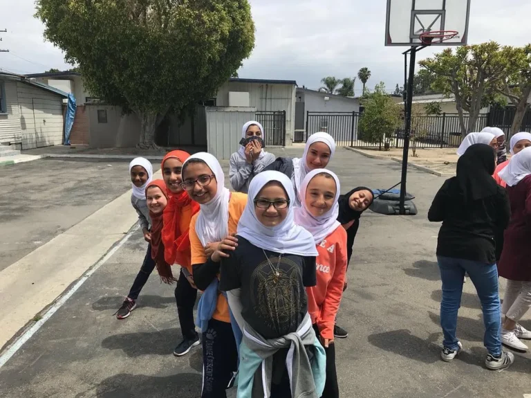 Girls from the shelter community smiling together in the courtyard