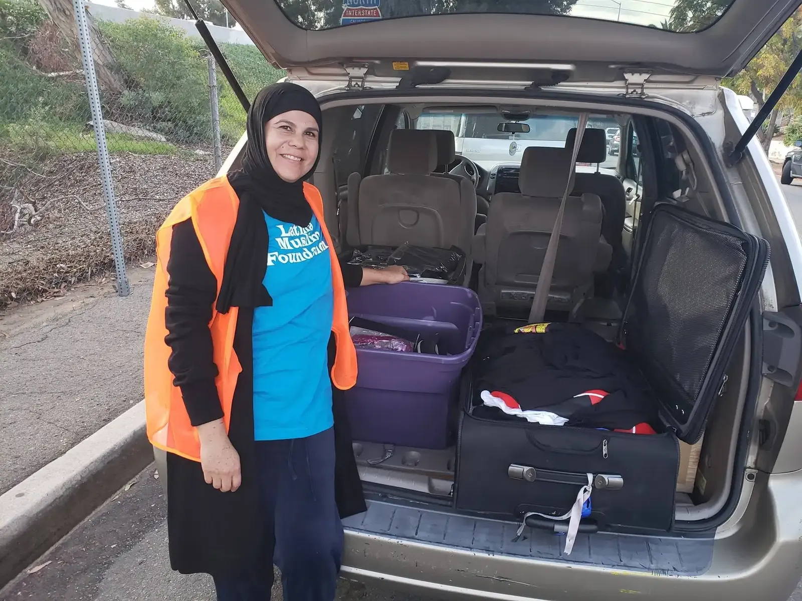 Sister Sonia Garcia smiling beside a van loaded with donated supplies for refugees