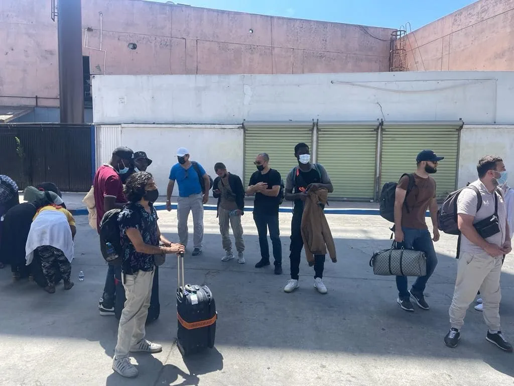 Newly arrived refugees with their luggage gathering outside, ready to be welcomed to the shelter