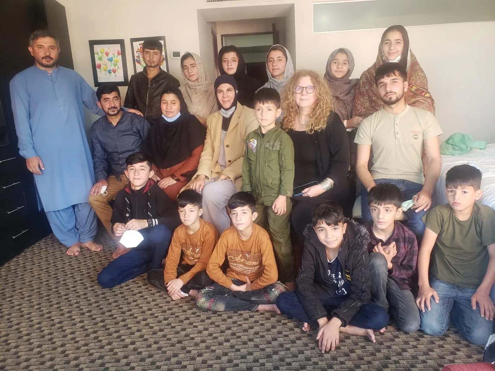 A large family group gathered together with ALMA volunteers