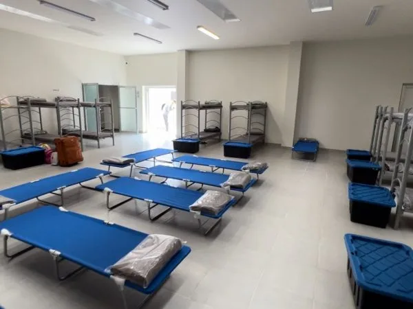 Rows of cots with fresh bedding in the shelter dormitory