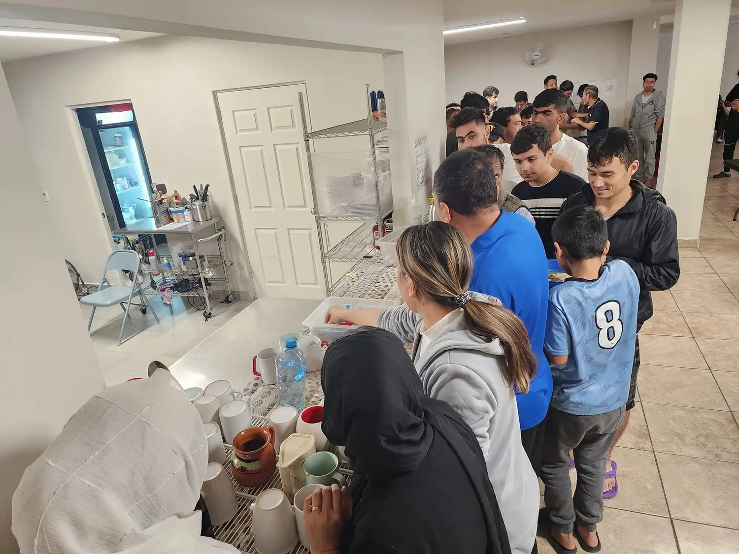 Refugee families lining up at the shelter's serving counter for a meal