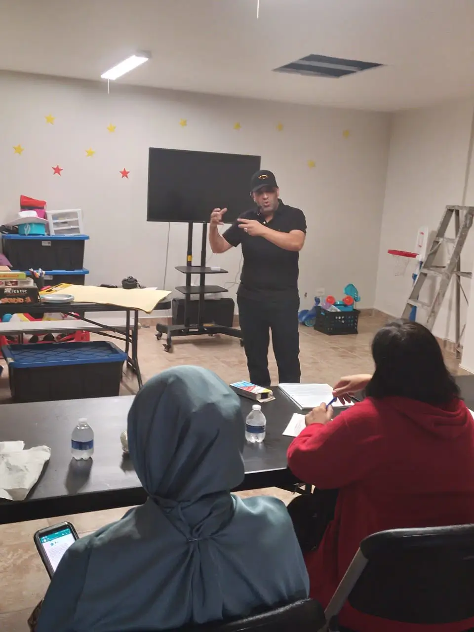 A teacher leading a language class for women seated at a table