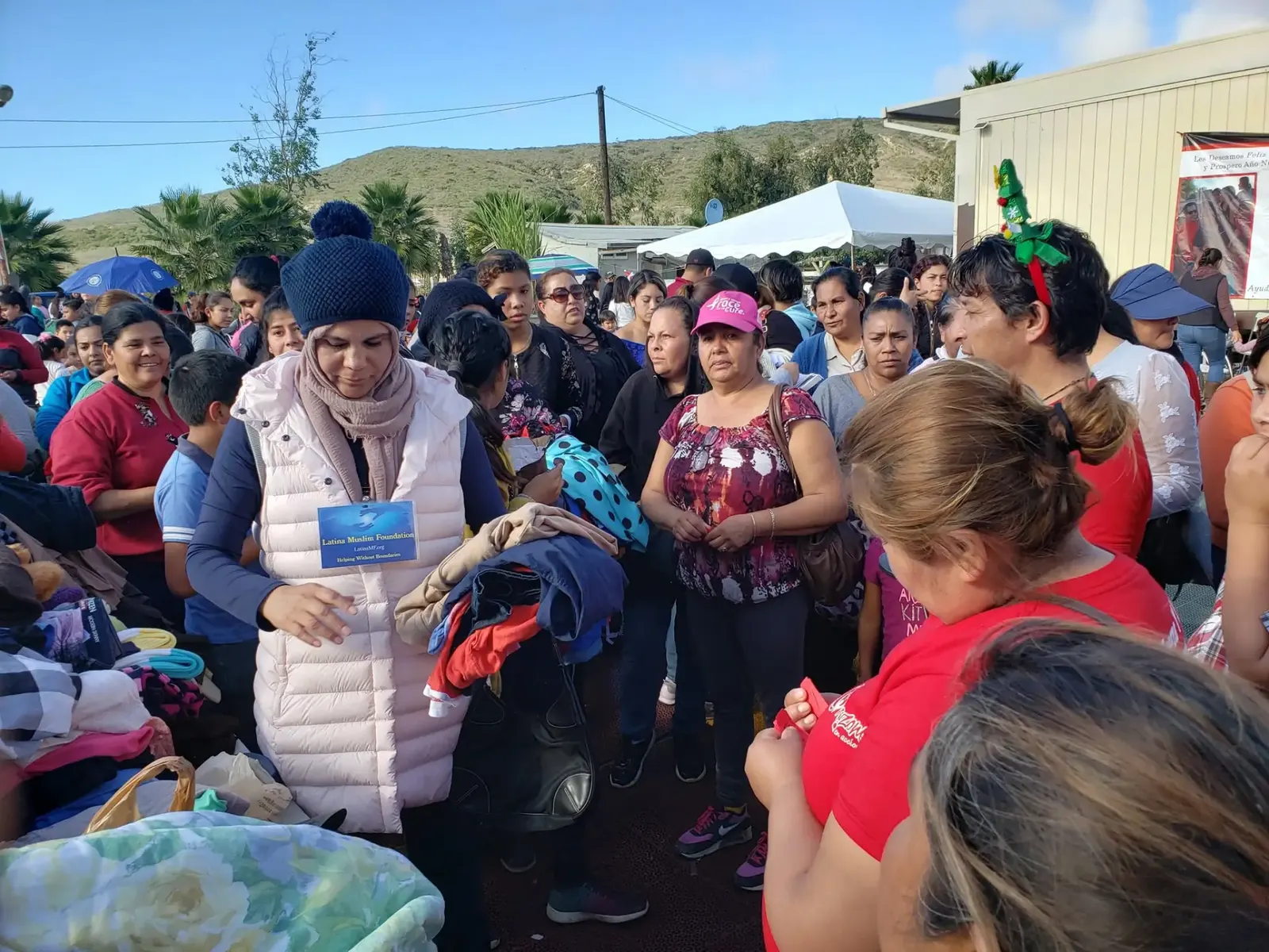 A Latina Muslim Foundation volunteer handing out warm clothing to families at a community distribution